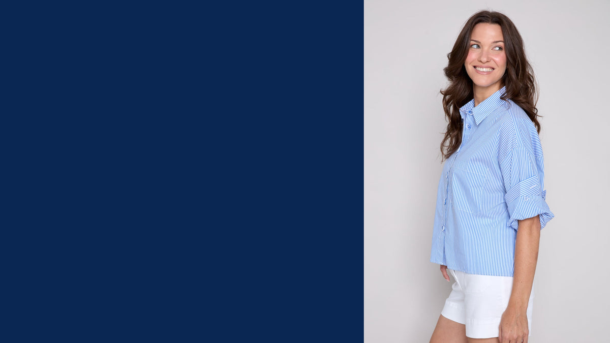 A woman wearing a light blue button-up shirt and white shorts, standing against a light gray background on the right side of a split canvas with a large dark blue block on the left.